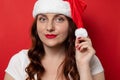 Smiling beautiful young girl with santa hat expressing happy emotions smiles at camera on gray wall background Royalty Free Stock Photo