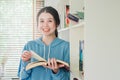 Smiling beautiful young girl standing in the library at home with books, Woman reading a book Royalty Free Stock Photo