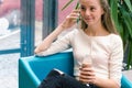 Smiling beautiful young girl talking on phone and drinking cocktail at the cafe. Portrait of beautiful smiling woman sitting on a Royalty Free Stock Photo