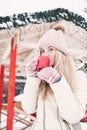 Smiling beautiful young woman drinks a hot cocoa outdoor. Royalty Free Stock Photo