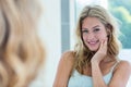 Smiling beautiful young woman looking at herself in the bathroom mirror Royalty Free Stock Photo