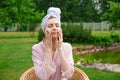 Smiling beautiful young woman with towel on head hold cotton pad cleansing face Royalty Free Stock Photo