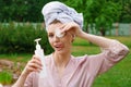 Smiling beautiful young woman with towel on head hold cotton pad cleansing face Royalty Free Stock Photo