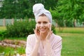 Smiling beautiful young woman with towel on head hold cotton pad cleansing face Royalty Free Stock Photo