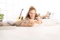 smiling Beautiful young woman using a smart phone lying on living room wooden floor in comfortable home Royalty Free Stock Photo