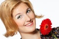 A smiling beautiful young woman in a white dress with a bright red flower near her face Royalty Free Stock Photo