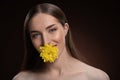 Smiling beauty model with bare shoulders holding a flower in her mouth with a beauty skin and long hair looking at Royalty Free Stock Photo