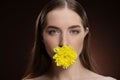 Smiling beauty model with bare shoulders holding a flower in her mouth with a beauty skin and long hair looking at Royalty Free Stock Photo