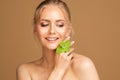 Smiling Beauty Model Smooth Skin with Mint. Woman Face and Body Health Care. Blond Girl with Wet Hair Holding Fresh Green Leaves Royalty Free Stock Photo