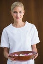 Smiling beauty therapist holding bowl of rose petals Royalty Free Stock Photo