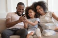 Smiling biracial family with kid laugh enjoy video on cell Royalty Free Stock Photo