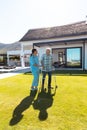 Smiling biracial female doctor assisting caucasian senior man in walking with walker in yard Royalty Free Stock Photo