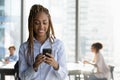 Smiling biracial female manager use phone at work text message