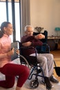 Smiling biracial female physiotherapist looking at caucasian senior man lifting dumbbell at home Royalty Free Stock Photo