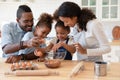 Smiling biracial little children involved in preparing breakfast with parents.