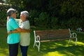 Smiling biracial senior couple looking and embracing while standing against plants in park Royalty Free Stock Photo