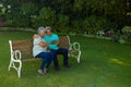 Smiling biracial senior couple using digital tablet while sitting on bench against plants in park Royalty Free Stock Photo