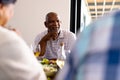 Smiling biracial senior man looking at friends while having lunch at dining table in nursing home Royalty Free Stock Photo