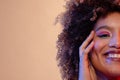 Smiling biracial woman with curly hair in pink eyeshadow and lipstick touching face, copy space Royalty Free Stock Photo