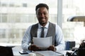 Smiling black businessman looking at camera at desk in office or legal firm