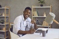 Smiling black businessman looking at camera sitting at desk with laptop in home office Royalty Free Stock Photo