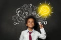 Smiling black child student with lightbulb on blackboard background. Brainstorming and idea concept