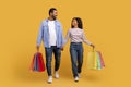 Smiling black couple carrying bright shopping bags, walking and holding hands Royalty Free Stock Photo