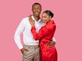 Smiling black couple embracing, woman in red dress, man in white shirt, pink background Royalty Free Stock Photo