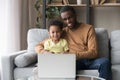 African father and little son watching cartoons on laptop