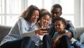 Smiling black family relax together watching cartoons on smartphone Royalty Free Stock Photo