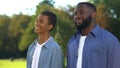 Smiling black father and male child standing outdoors and enjoying park view