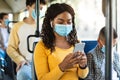 Beautiful smiling black woman in mask listening music in bus Royalty Free Stock Photo