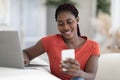 Smiling Black Female Freelancer Using Smartphone And Working With Laptop At Home Royalty Free Stock Photo