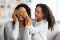 Smiling black girl closing her mother eyes, making surprise