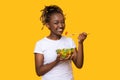 Smiling black girl eating fresh salad over yellow Royalty Free Stock Photo