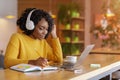 Smiling black girl with headset studying online, using laptop Royalty Free Stock Photo