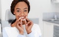 Smiling black girl holding invisible aligner, modern teeth trainer