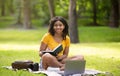 Smiling black girl studying online on laptop at summer park Royalty Free Stock Photo