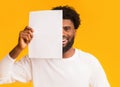 Smiling black guy covering half of his face with paper Royalty Free Stock Photo