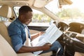 Black guy driver reading map while sittig in car Royalty Free Stock Photo