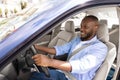 Smiling black guy driving new car in city Royalty Free Stock Photo