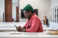 Smiling African guy student using smartphone during study break, sitting at desk in library Royalty Free Stock Photo