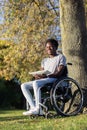 Smiling Black guy in wheelchair enjoying lunch in city park Royalty Free Stock Photo