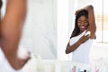 Smiling Black Lady Applying Roller Deodorant To Armpit Zone In Bathroom Royalty Free Stock Photo