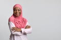 Smiling black lady in hijab posing on grey