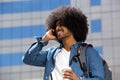 Smiling black man with afro using mobile phone in the city Royalty Free Stock Photo