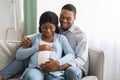 Smiling black man hugging his pregnant woman, sitting on sofa Royalty Free Stock Photo