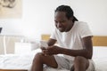 Smiling Black Man Messaging On Smartphone While Relaxing In Bedroom At Home Royalty Free Stock Photo