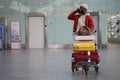 Smiling Black man pushing luggage trolley walking after arrival at airport, talking on mobile phone. Royalty Free Stock Photo