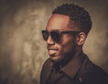 Smiling black man with sunglasses posing on dark background. Royalty Free Stock Photo